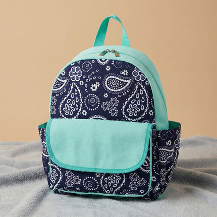 Red To Purple personalized preschool backpack features a navy-white paisley pattern, with a solid mint front flap pocket and trim, resting on a textured grey carpet.
