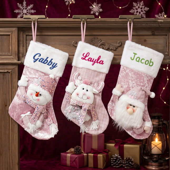 3 pink velvet burlap Christmas stockings hanging on a wooden mantel with embroidered name samples
